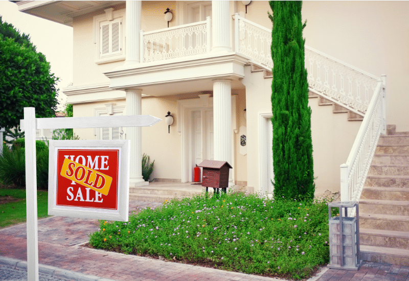 A house with a "For Sale" sign in front of it